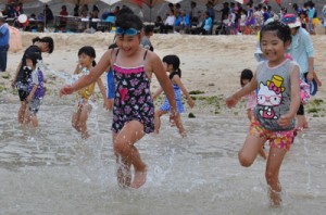 海開きで、水しぶきを上げながら海へと向かう子どもたち＝２４日、和泊町のワンジョビーチ